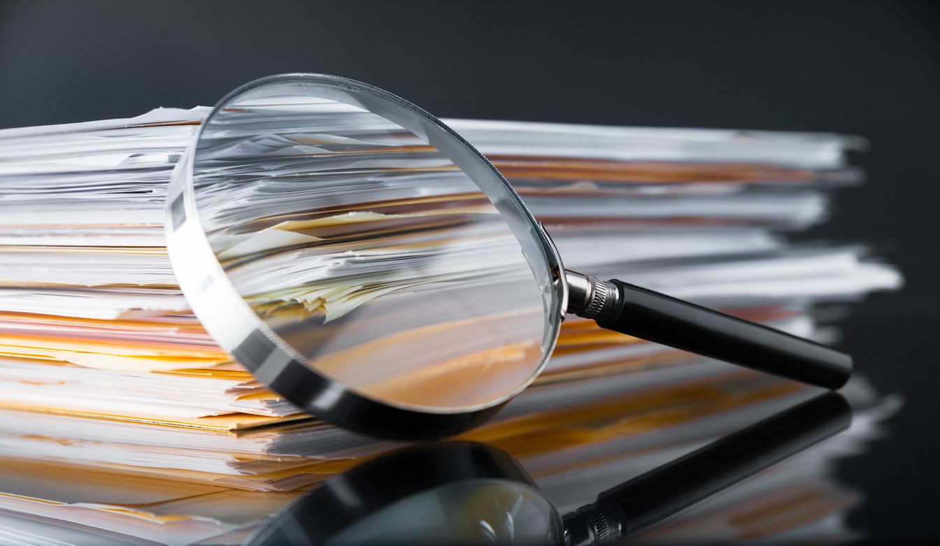 stack of files with magnifying glass on top showing data review